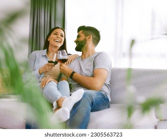 Portrait of a lovely young couple drinking wine together on sofa  at home - Powered by Shutterstock