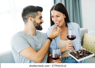 Portrait of a lovely young couple eating chocolate praline together on sofa  at home