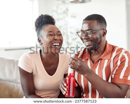 Portrait of a lovely young couple having fun and laughing sharing a drink together at home