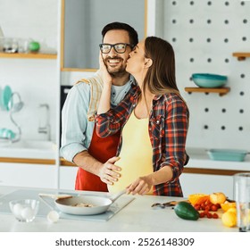 Portrait of a lovely young couple, a pregnant woman,  preparing a healthy meal in the kitchen - Powered by Shutterstock