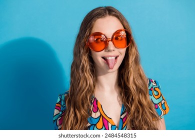 Portrait of lovely young girl squint eyes show tongue wear top isolated on blue color background