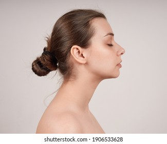 Portrait Of Lovely Young Woman In Profile With Bared Shoulders. Studio Shot On Light Background