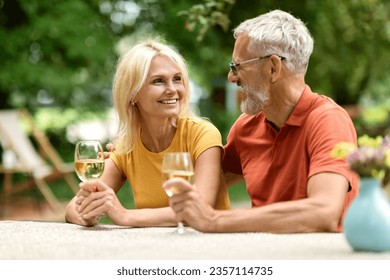 Portrait Of Loving Married Senior Couple Drinking Wine Outdoors, Happy Mature Spouses Sitting At Table In Garden, Having Picnic Outside, Looking And Smiling To Each Other, Celebrating Anniversary - Powered by Shutterstock