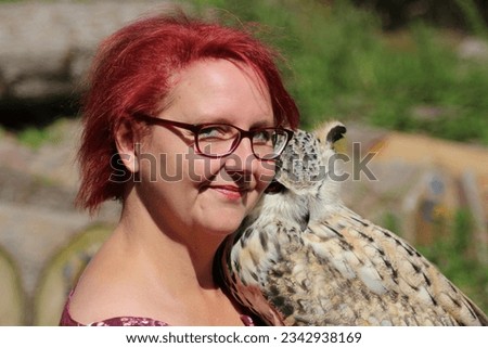 Portrait of a loving woman holding an owl outdoors