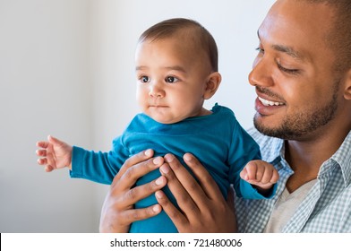 Portrait Of Loving Young Man Holding Baby At Home. Close Up Of Happy Black Father With His Little Boy Smiling. Young African Father Embracing His Cute Toddler.