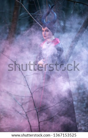 Portrait of Magical Maleficent Woman with Horns Posing in Spring Empty Forest with Smoky Background. Vertical Image Orientation