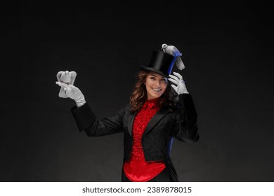 A portrait of a magician in a magician's costume and black top hat performing magic tricks with white doves against a dark background - Powered by Shutterstock