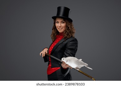 A portrait of a magician in a magician's costume and black top hat performing magic tricks with white doves against a dark background - Powered by Shutterstock