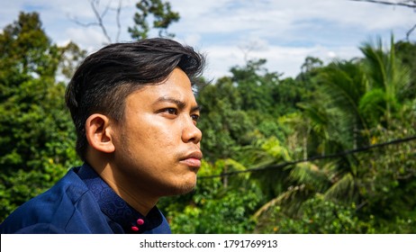 A Portrait Of A Malay Man Model Wearing A Blue Traditional Baju Melayu With Green Nature Background.