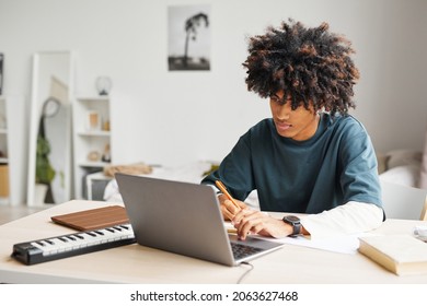 Portrait Of Male African-American Student Using Laptop While Doing Homework In College Dorm, Copy Space