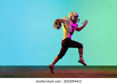 Portrait of male american football player playing, training isolated on blue background in neon light. Concept of sport, movement, achievements. Copy space for ad - Powered by Shutterstock