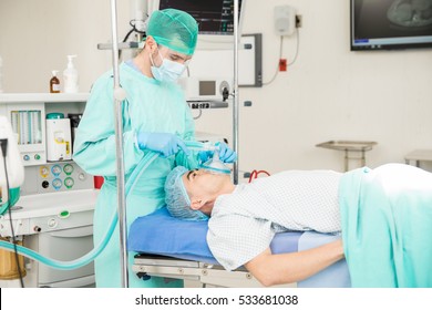 Portrait Of A Male Anesthesiologist Administering A Sedative To A Patient Before Surgery