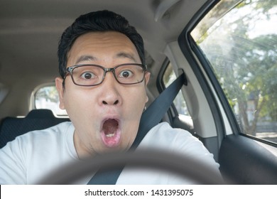 Portrait of male Asian driver shocked and panic about to have crash accident, close up with open mouth 