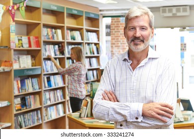 Portrait Of Male Bookstore Owner With Customer In Background