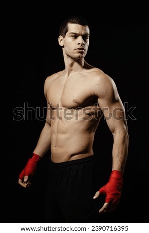 Portrait of male boxer posing in boxing stance against black background.