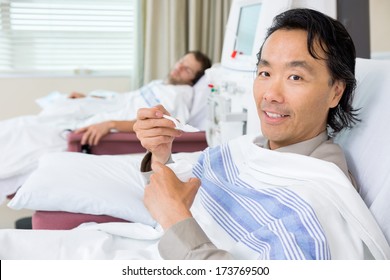 Portrait Of Male Cancer Patient Eating Crushed Ice During Dialysis At Hospital Room