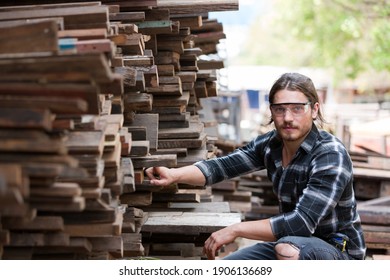 Portrait Of Male Carpenter Wearing Safety Goggles At Work. Woodworker Examining Wood At Woodwork Workshop