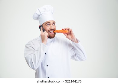 Portrait of a male chef cook talking on the phone and eating carrot isolated on a white background - Powered by Shutterstock