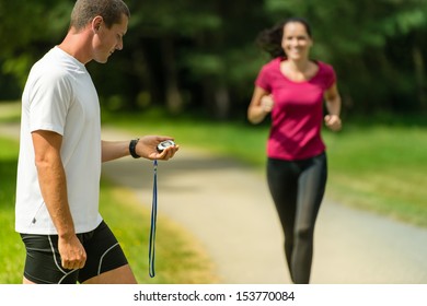 Portrait of male coach timing runner in a park - Powered by Shutterstock