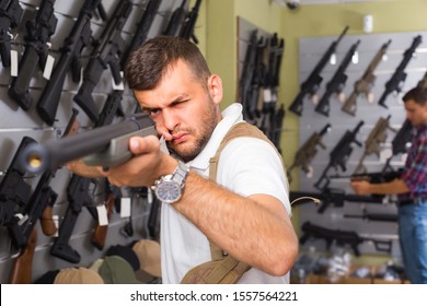 Portrait of male customer which is choosing air-powered gun in army market.  - Shutterstock ID 1557564221