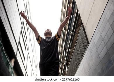 Portrait Of A Male Dancer Performing An Urban Modern Dance With Some Buildings Behind In London. He Is Mixed Race And Wears Black Outfit.