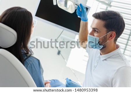 portrait of male dentist adjusting lamp in the hospital