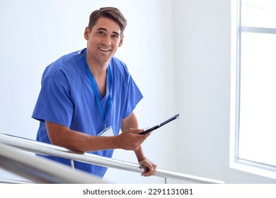 Portrait Of Male Doctor Or Nurse With Digital Tablet Checking Patient Notes On Stairs In Hospital - Powered by Shutterstock