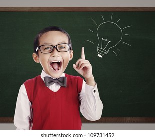 Portrait Of Male Elementary School Student With Lightbulb Picture On Blackboard