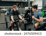 Portrait of male exercising support under supervision of personal coach. Trainer helping beginner sportsman for correct doing Scott Curls with barbell, lifting up EZ-bar sitting on preacher curl bench