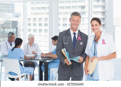 Portrait of male and female doctors with medical reports against pink breast cancer awareness ribbon - Powered by Shutterstock