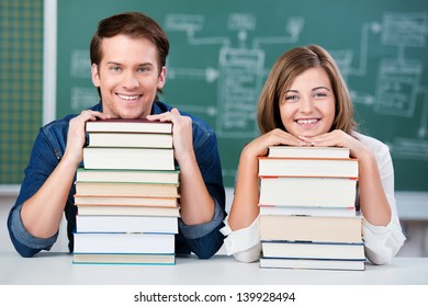 Portrait of male and female students resting chin on stack of books at classroom desk - Powered by Shutterstock