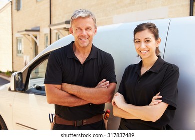 Portrait of male and female trade workers standing by a van