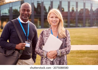 Portrait Of Male And Female University Or College Tutor Outdoors With Campus Building In Background