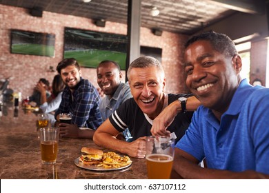 Portrait Of Male Friends At Counter In Sports Bar