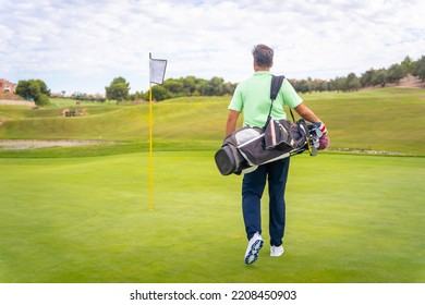 Portrait of male golfer walking down fairway carrying bags, playing golf - Powered by Shutterstock