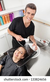 Portrait Of Male Hairstylist Washing Client's Hair In Beauty Parlor