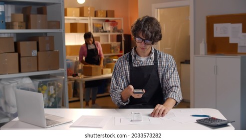 Portrait Of Male Manager Scan Qr-code With Smartphone App In Warehouse. Post Office Worker Scanning Qr Code On Receipt With Cellphone