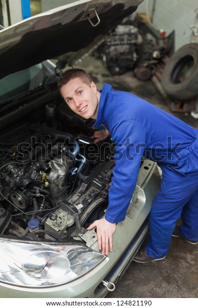 Portrait of male\
mechanic examining car\
engine