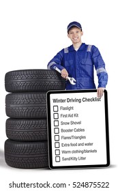 Portrait Of A Male Mechanic Holding A Wrench And Showing Tips Of Winter Driving While Standing With Tires, Isolated On White Background