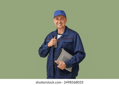 Portrait of male mechanic with laptop on green background - Powered by Shutterstock