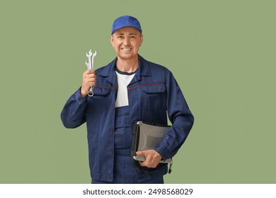 Portrait of male mechanic with laptop and tools on green background - Powered by Shutterstock