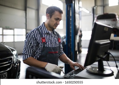 Portrait Of Male Mechanic Touching Computer Monitor In Auto Repair Shop