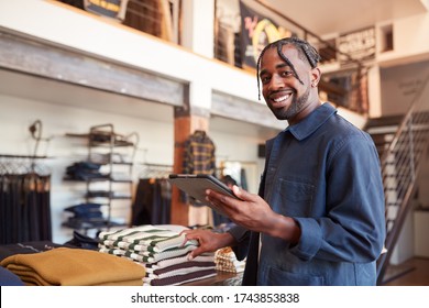 Portrait Of Male Owner Of Fashion Store Using Digital Tablet To Check Stock In Clothing Store