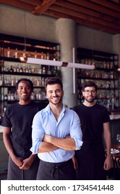 Portrait Of Male Owner Of Restaurant Bar With Team Of Waiting Staff Standing By Counter