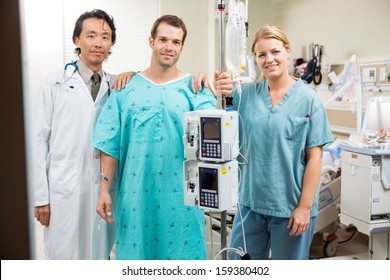 Portrait of male patient with doctor and nurse standing by machine stand in hospital - Powered by Shutterstock