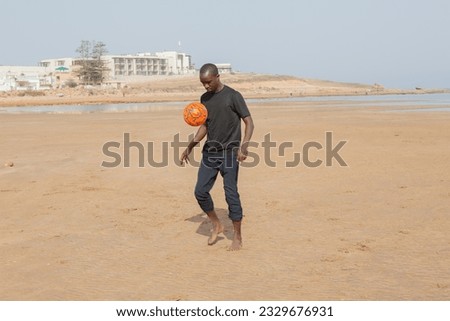 Portrait of a male, person of color, in his thirties, playing football at the beach in Morocco, north africa