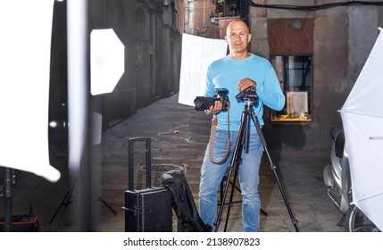 Portrait Of Male Photographer Standing With Camera Among Professional Photo Equipment On The Old City Street