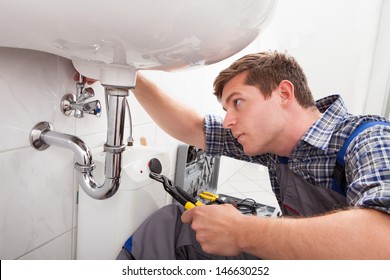 Portrait of male plumber fixing a sink in bathroom