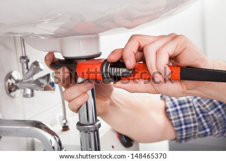Portrait of male plumber fixing a sink in bathroom