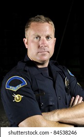 A Portrait Of A Male Police Officer With His Arms Crossed.